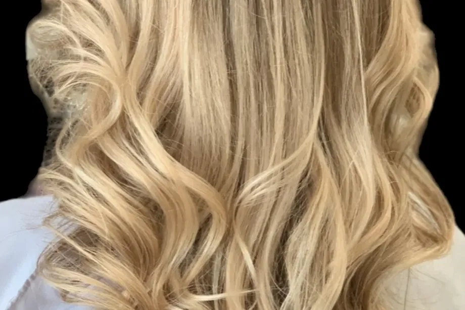 Long blonde waves with hair extensions, a real client result of hair extension methods in Boca Raton